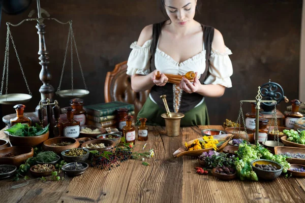 Natural medicine concept. Vintage pharmacist preparing natural medicament. Brass mortar and  bottles. Rustic table. Assorted dry herbs in bowls.