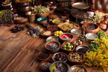 Doğal tıp geçmişi. Kâselerde çeşitli kuru otlar ve rustik ahşap masa üzerinde pirinç havan..