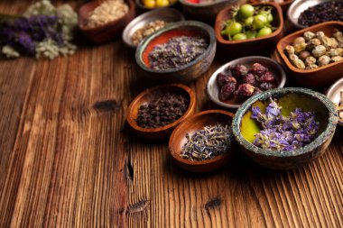 Doğal tıp geçmişi. Kâselerde çeşitli kuru otlar ve rustik ahşap masa üzerinde pirinç havan..