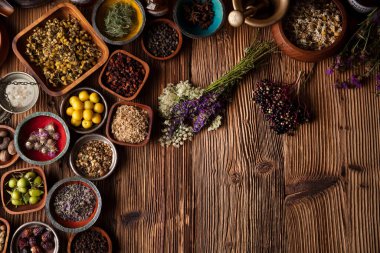 Doğal tıp geçmişi. Kâselerde çeşitli kuru otlar ve rustik ahşap masa üzerinde pirinç havan..