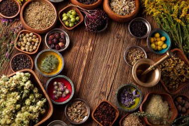 Doğal tıp geçmişi. Kâselerde çeşitli kuru otlar ve rustik ahşap masa üzerinde pirinç havan..