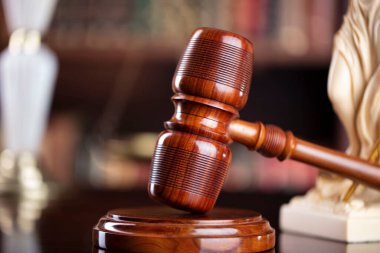 Hakimler kahverengi masa ve kitaplığın arka planında tokmak var. Hukuk ve adalet kavramı.