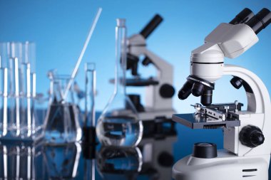 Coronavirus salgını teması. Hızlı covid testleri ve anti-covid aşısıyla ilgili bilimsel araştırma. Mavi arka planda deney tüpleri, mikroskop ve test tüpleri..