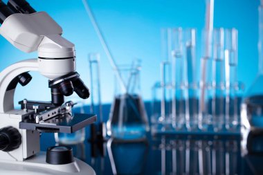 Coronavirus salgını teması. Hızlı covid testleri ve anti-covid aşısıyla ilgili bilimsel araştırma. Mavi arka planda deney tüpleri, mikroskop ve test tüpleri..