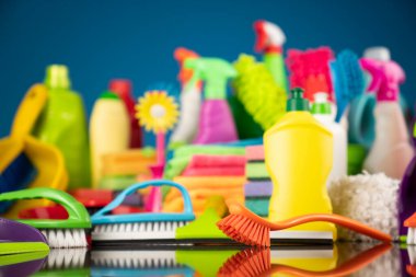 Ev ve ofis temizliği teması. Kırıcı kahverengi masa ve mavi arkaplan üzerindeki renkli temizlik seti.