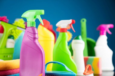 Ev ve ofis temizliği teması. Kırıcı kahverengi masa ve mavi arkaplan üzerindeki renkli temizlik seti.