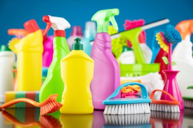 Ev ve ofis temizliği teması. Kırıcı kahverengi masa ve mavi arkaplan üzerindeki renkli temizlik seti.