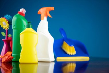 Ev ve ofis temizliği teması. Kırıcı kahverengi masa ve mavi arkaplan üzerindeki renkli temizlik seti.