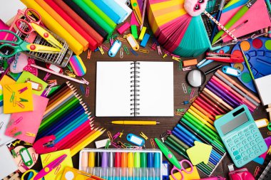 Okul malzemeleri. Kahverengi masada izole edilmiş renkli okul aksesuarlarının bileşimi. Üst görünüm.