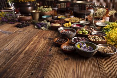 Doğal tıp geçmişi. Kâselerde çeşitli kuru otlar ve rustik ahşap masa üzerinde pirinç havan..