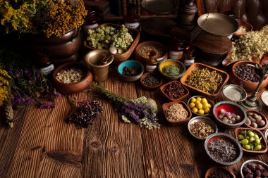 Doğal tıp geçmişi. Kâselerde çeşitli kuru otlar ve rustik ahşap masa üzerinde pirinç havan..