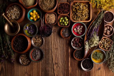Doğal tıp geçmişi. Kâselerde çeşitli kuru otlar ve rustik ahşap masa üzerinde pirinç havan..