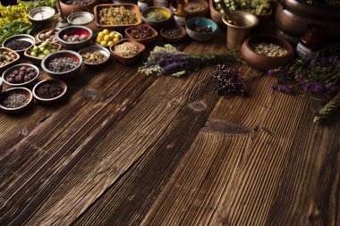 Doğal tıp geçmişi. Kâselerde çeşitli kuru otlar ve rustik ahşap masa üzerinde pirinç havan..