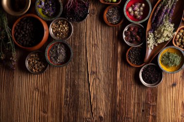 Doğal tıp geçmişi. Kâselerde çeşitli kuru otlar ve rustik ahşap masa üzerinde pirinç havan..