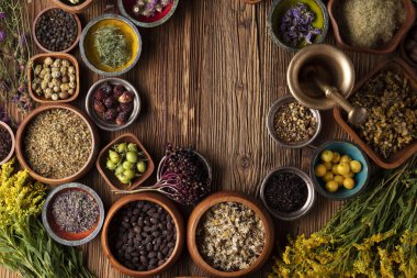 Doğal tıp geçmişi. Kâselerde çeşitli kuru otlar ve rustik ahşap masa üzerinde pirinç havan..