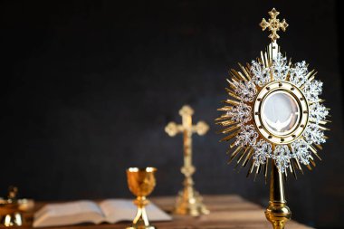 Katolik dini kavramı. Katolik sembolleri kompozisyonu. Haç, Monstrance, Kutsal İncil ve ahşap sunakta altın kadeh.. 