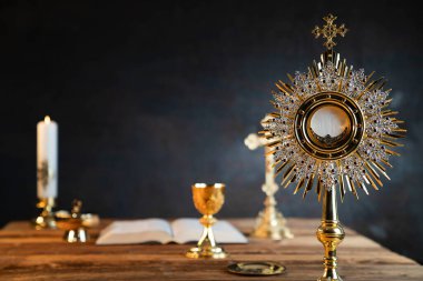 Katolik dini kavramı. Katolik sembolleri kompozisyonu. Haç, Monstrance, Kutsal İncil ve ahşap sunakta altın kadeh.. 