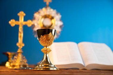 Katolik dini kavramı. Katolik sembolleri kompozisyonu. Haç, Monstrance, Kutsal İncil ve ahşap sunakta altın kadeh.. 
