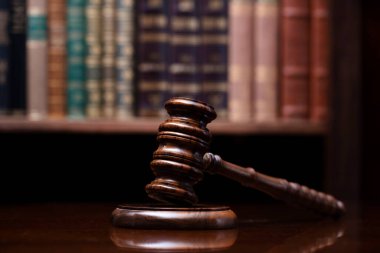 Hukuk teması. Yargıç odası. Hakimler kahverengi masasında tokmak var. Kitaplıkta yasal kitap koleksiyonu.