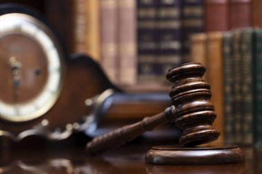 Hukuk teması. Yargıç odası. Hakimler kahverengi masasında tokmak var. Kitaplıkta yasal kitap koleksiyonu.