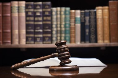 Hukuk teması. Yargıç odası. Hakimler kahverengi masasında tokmak var. Kitaplıkta yasal kitap koleksiyonu.