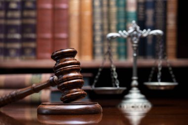 Hukuk teması. Yargıç odası. Hakimler kahverengi masasında tokmak var. Kitaplıkta yasal kitap koleksiyonu.