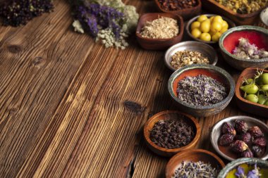 Doğal tıp teması. Kâselerde çeşitli kuru otlar ve rustik ahşap masa üzerinde pirinç havan..