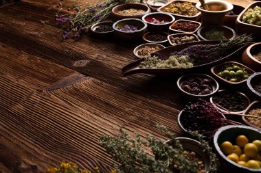 Doğal tıp teması. Kâselerde çeşitli kuru otlar ve rustik ahşap masa üzerinde pirinç havan..