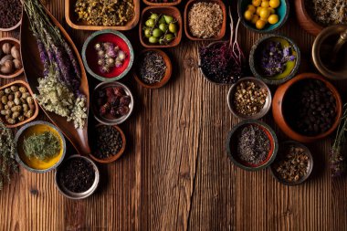 Doğal tıp teması. Kâselerde çeşitli kuru otlar ve rustik ahşap masa üzerinde pirinç havan..