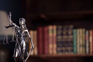 Hukuk ve adalet kavramı. Bu heykel avukatların ofisinde. Arkaplanda hukuk kitapları olan bir kitaplık.