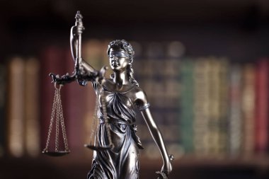 Hukuk ve adalet kavramı. Bu heykel avukatların ofisinde. Arkaplanda hukuk kitapları olan bir kitaplık.