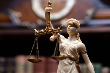 Hukuk ve adalet kavramı. Bu heykel avukatların ofisinde. Arkaplanda hukuk kitapları olan bir kitaplık.