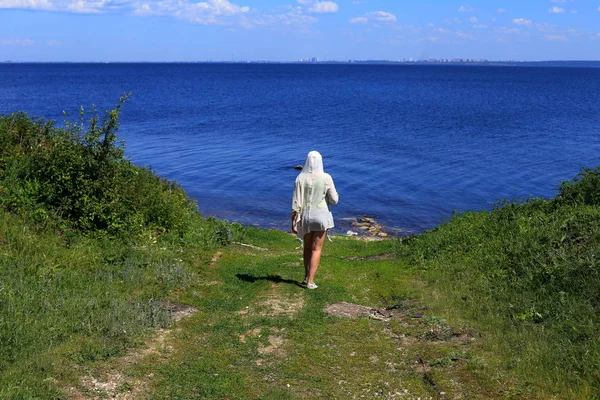 Beyaz kazaklı kadın. arkadan görüntüleyin. yolda gidiyor. yaz ve yeşil çimen.