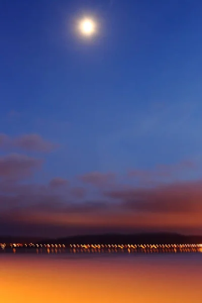 fantasy and relaxation in bright colors of natureAbstract blurred image. lights of a distant bridge and a high moon. low clouds