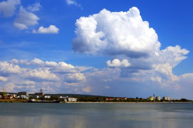 Senin şehir bakmak ve doğası tadını çıkarın. Parlak güzel bulutlar. Ufukta nehrin kıyısında şehir ve bağlantı noktası var. Doğanın güzelliği sıcak bir yaz.