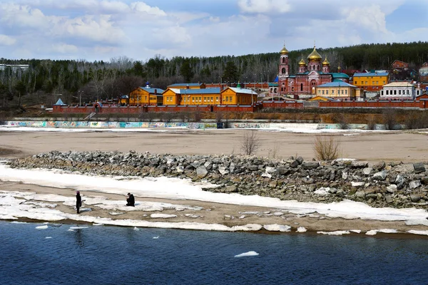 Nature and spirituality are one and inseparable.Early spring. on the river bank there is a male temple. a man takes pictures of a woman. sky and forest.