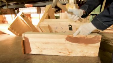 Bir işçi bir çivi bir çekiç ile bir yönetim kurulu üretim içine çekiç. Ellerini kapatın. Arka planda ahşap bir modeldir.