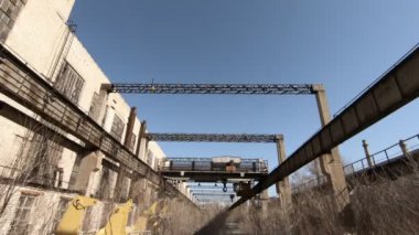 Eski fabrikanın atölyeleri. Büyük, ağır bir vinç. Mavi gökyüzüne karşı metal yapı.