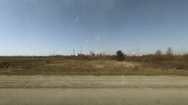 Yolda hareket eden bir arabadan ateş etmek. Bahar ve sıcak berrak bir gün. Bitki boyunca seyahat edin.