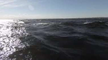 Mavi yüksek dalgalar ve bulutlarla mavi gökyüzü. Close. Temiz deniz havası. Gelen güneşten gelen suda parlak parlama.