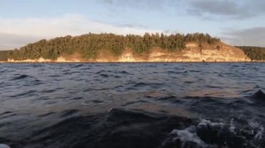 Denizde tekne ile hareket. Bir taraftan çekim. Bu taş sahil ve orman görülebilir. Temiz hava ve dalgalar, su sıçraması. Metin alanı. Atmosferik video.