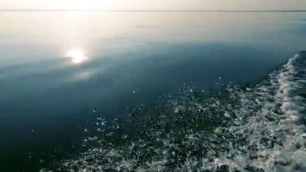 傍晚的夕阳和明亮的倒影 平静的大海和光滑的海水 地平线在阴霾中 从船上喷出 文本的空间 大气视频 — 图库视频影像