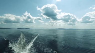 Denizde tekne ile hareket. Kıçından ateş ettim. Sen motor, uzak ufuk, temiz hava ve dalgalar, su sıçraması gelen uyanma görebilirsiniz. Metin alanı. Atmosferik video.