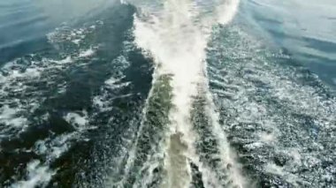 Denizde tekne ile hareket. Kıçından ateş ettim. Sen motor, uzak ufuk, temiz hava ve dalgalar, su sıçraması gelen uyanma görebilirsiniz. Metin alanı. Atmosferik video.