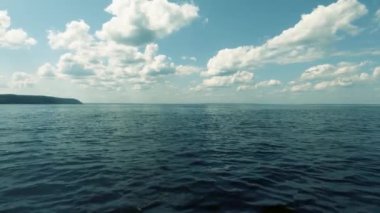 Tekne denizde duruyor. . Bir taraftan çekim. Temiz hava, sakin dalgalar ve suda küçük dalgalanmalar. Yüksek beyaz bulutlar. Metin alanı. Atmosferik video.
