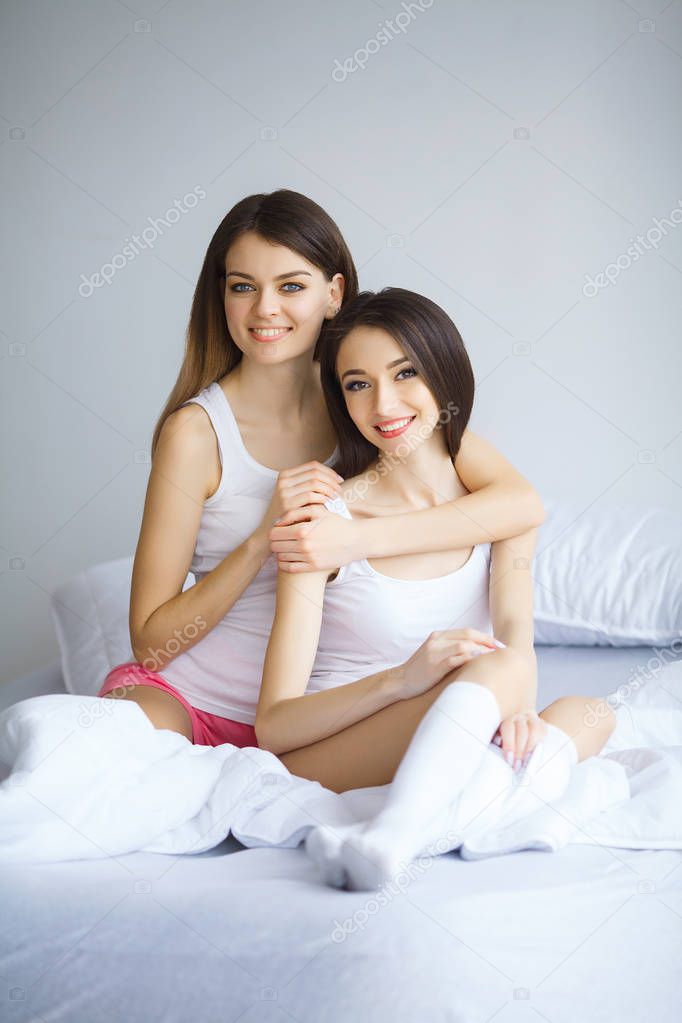 Portrait of two beautiful cheerful girls with beaming smiles huging