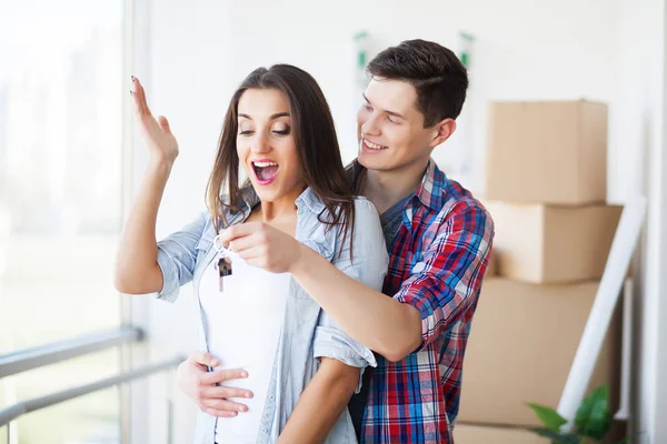 Sarılma, birlikte karton kutuları açma yeni ev anahtarları gösterilen çift