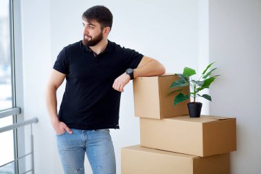 Genç adam düşüyor karton kutu. Yeni evine taşıdıktan