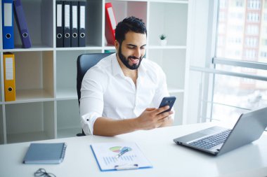 Masada oturan ve dizüstü bilgisayar kullanma office genç yakışıklı girişimci.