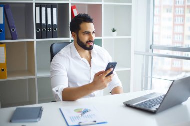 Masada oturan ve dizüstü bilgisayar kullanma office genç yakışıklı girişimci.